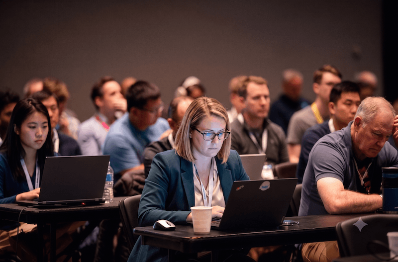 Attendees in business attire focused on laptops during a session